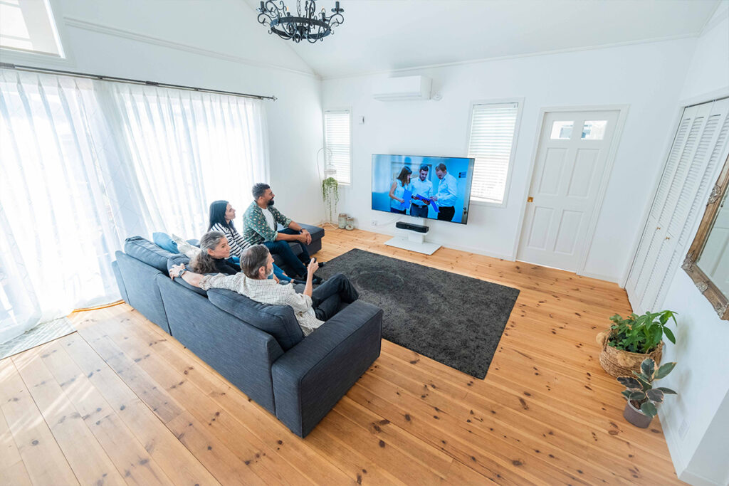 Family sitting in their house watching TV with Mirai Speaker attached.